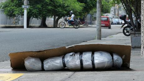 An abandoned corpse wrapped in plastic and covered with cardboard lies on a sidewalk in Guayaquil, Ecuador, on April 6.
