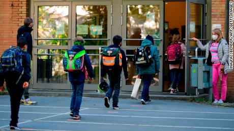 The children respect the rules of social removal when they enter Petri elementary school in Dortmund, western Germany, on Thursday, while the school reopens for some pupils.
