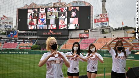 Cheerleaders pose in front of a big screen showing baseball fans cheering from their homes during the opening game of the new South Korean baseball season between SK Wyverns and Hanwha Eagles at Incheon's Munhak baseball stadium on Tuesday.