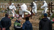 Old excavators bury a victim of COVID-19 while relatives and friends are at a safe distance, in a cemetery in Kolpino, outside St. Petersburg, on Friday.