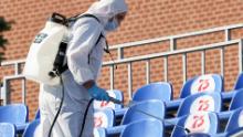 A sanitary worker in protective gear sprays disinfectant on seats in Red Square before the parade.