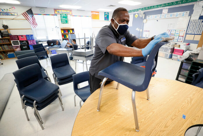 Custodian Tracy Harris cleans chairs in a classroom at Brubaker Elementary School on July 8 in Des Moines, Iowa.