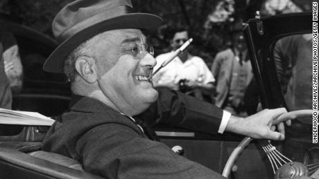 With a cigarette in a holder clenched in his teeth, a smiling Franklin Delano Roosevelt sits jauntily at the wheel of his convertible, Warm Springs, Georgia, 1939. (Photo by Underwood Archives/Getty Images)