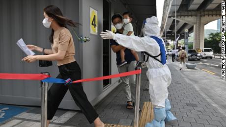 A health official wearing protective gear guides visitors at a Covid-19 coronavirus testing station in Seoul on August 18, 2020.