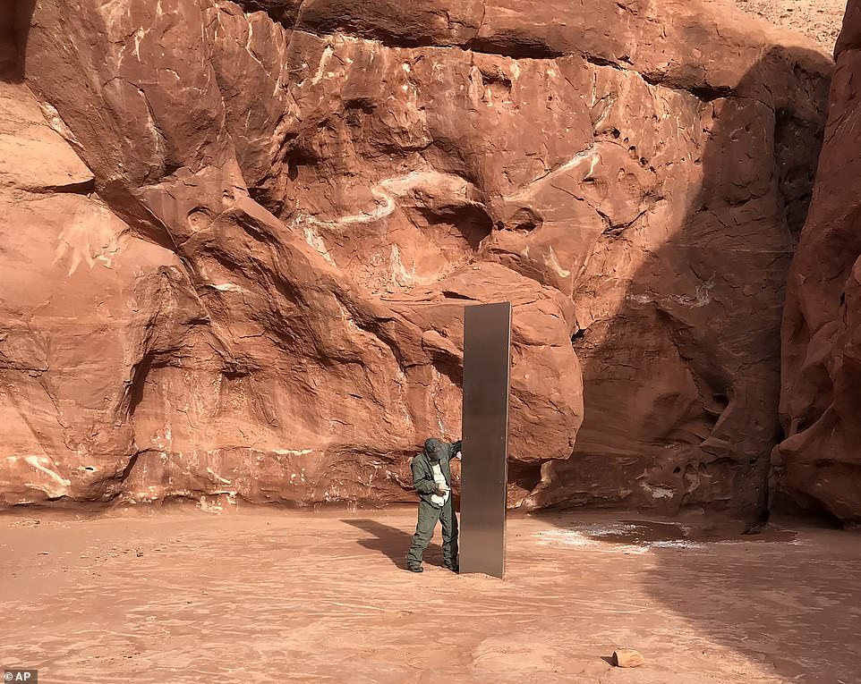 A photo provided by Utah Public Safety shows a state employee inspecting this mysterious metal monolith that was found planted in the ground in a remote area of ​​the Red Rock Desert earlier this week.