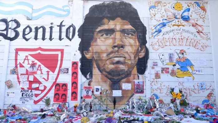Fans place offerings to late Diego Maradona in front of mural outside Argentinos Juniors&#39; Stadium Diego Maradona