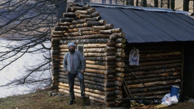 Ken with his log cabin soon after it was built in the early 1980s.